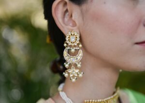 Close-up of a woman's ear adorned with luxurious gold earrings featuring pearls and gems.